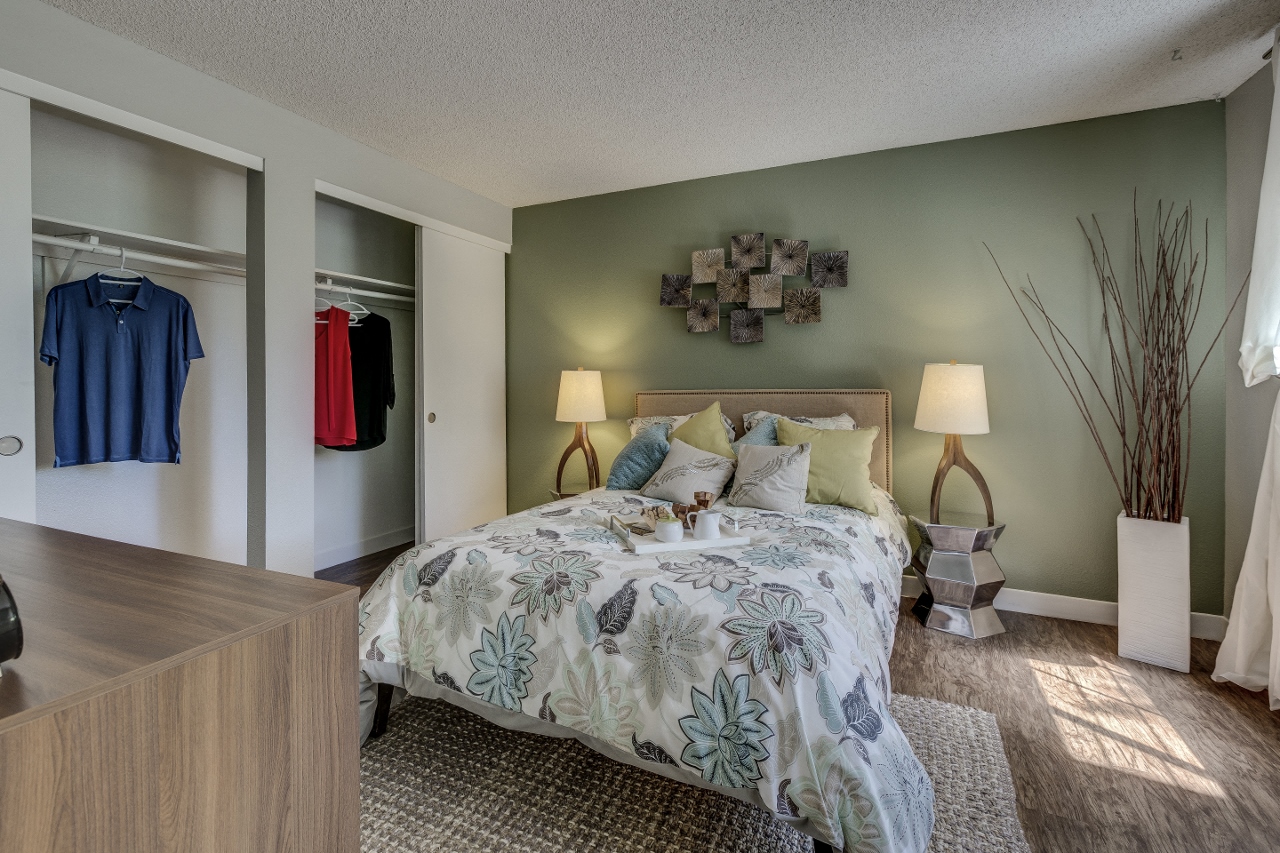 2-BR Apartments in West Beaverton, OR - Cedar Crest Apartments - Bedroom with Bed, Nightstands with Lamps, Wood-Style Flooring, Area Rug, and Wall Closet