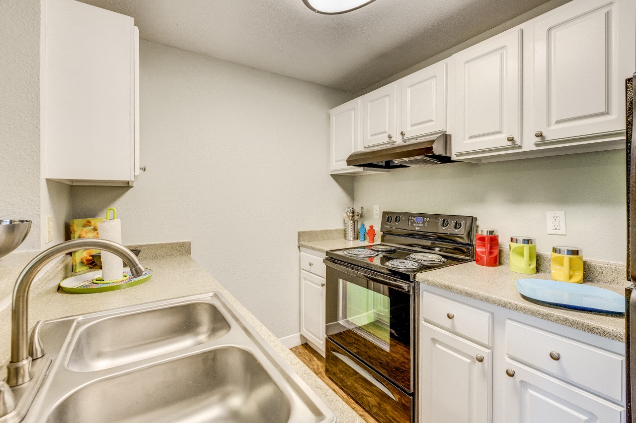 Beaverton, OR Apartments - MonteVista - Modern Kitchen with White Cabinetry, Stainless Steel Appliances, and Tan Granite-Style Countertops