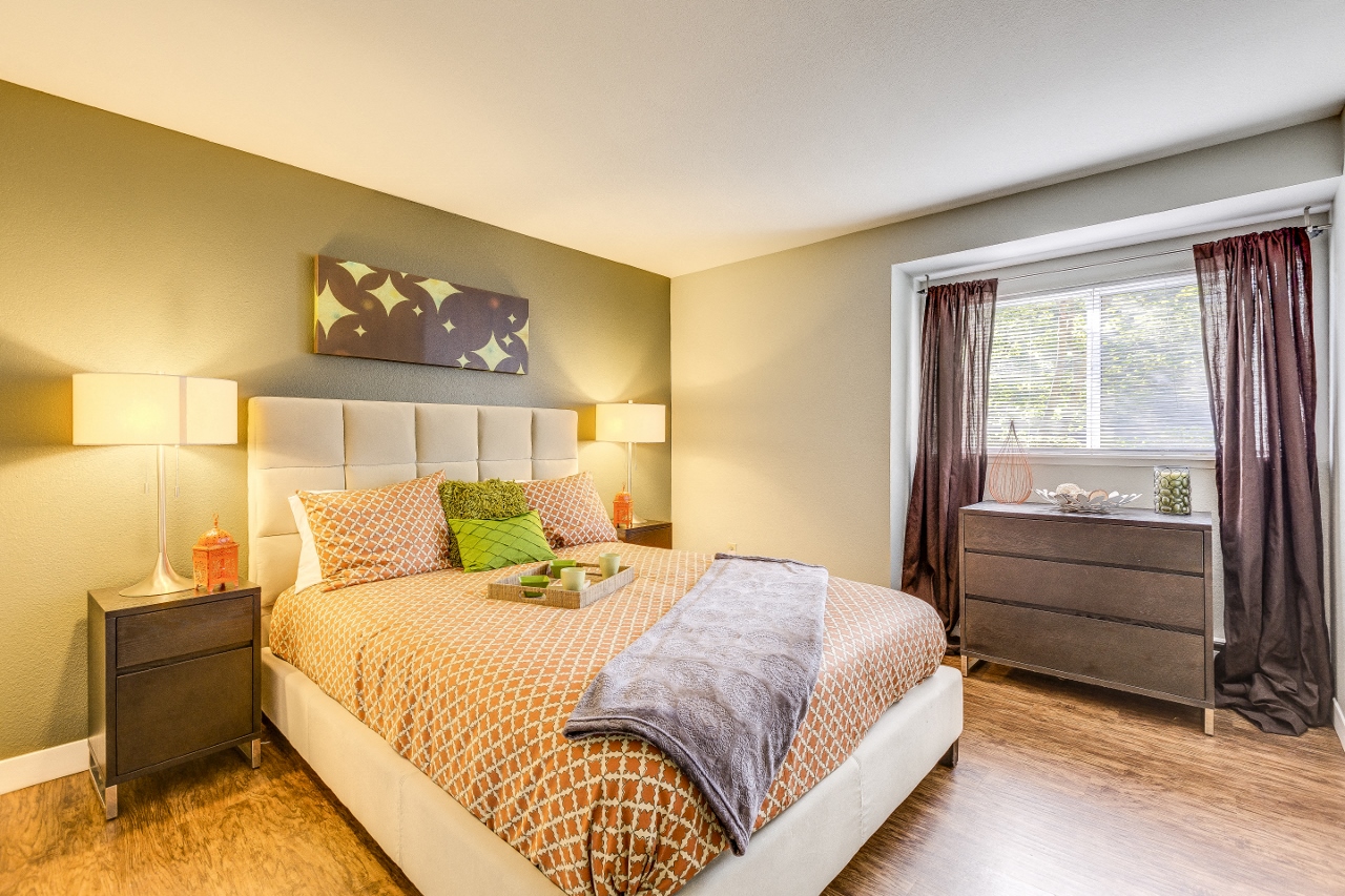 One Bedroom Apartments in Beaverton, OR - MonteVista - Furnished Bedroom with Plank Flooring, Bed, Nightstands with Lamps, Dresser, Window with Curtains, and Green Accent Wall
