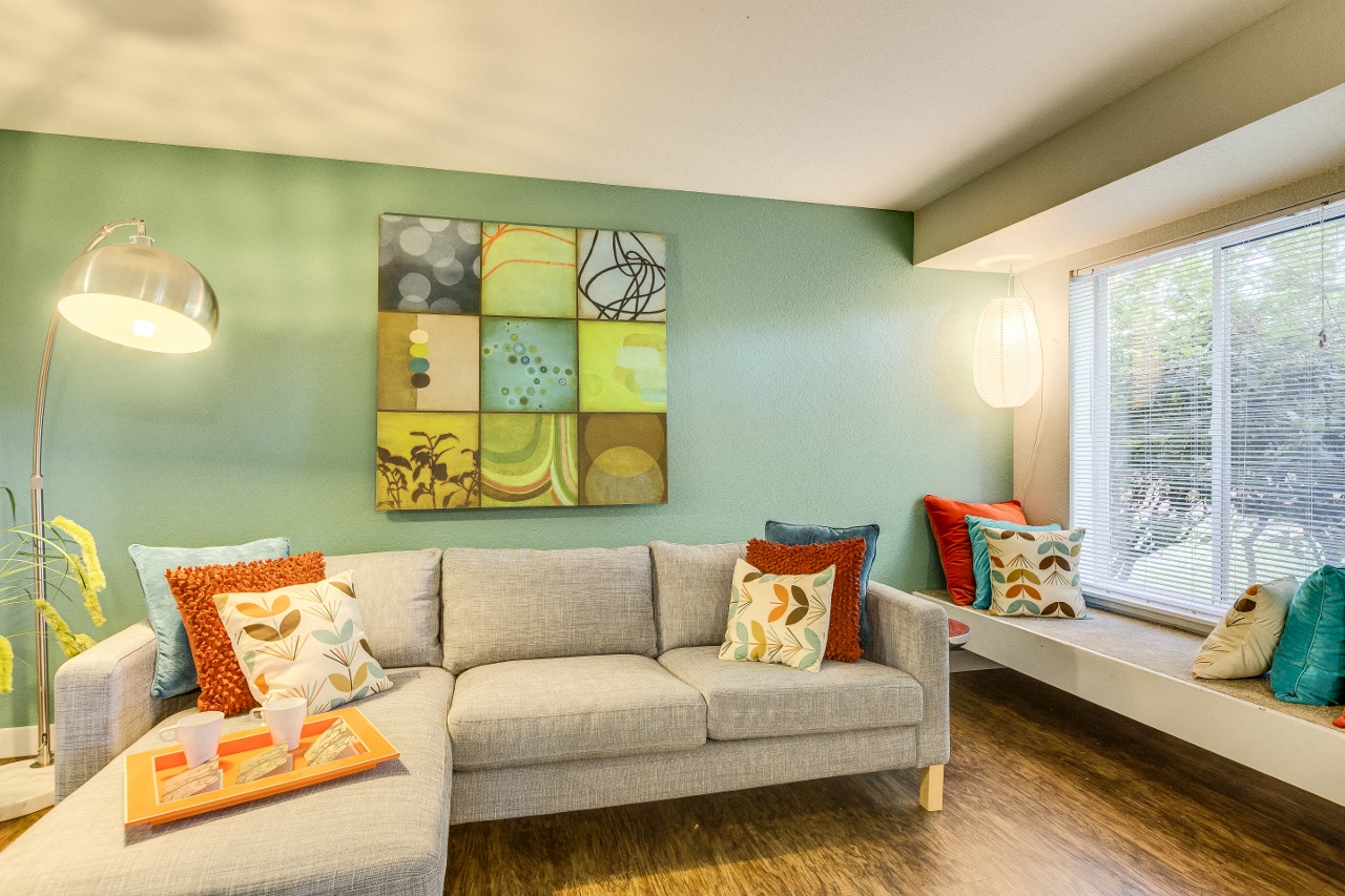 Beaverton Apartments - MonteVista - Relaxing Living Room with L Shaped Couch, Window Bench, Oversized Window, and Wood Flooring