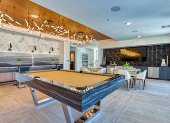 a pool table sits in the middle of a room with a bar in the background