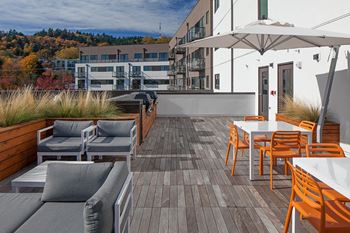 a roof deck with couches and chairs and a table with an umbrella