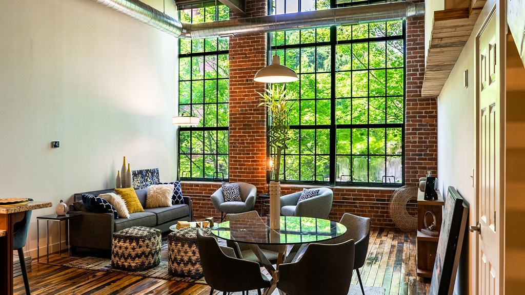 Modern loft apartment interior with exposed brick, large windows, and contemporary furniture.
