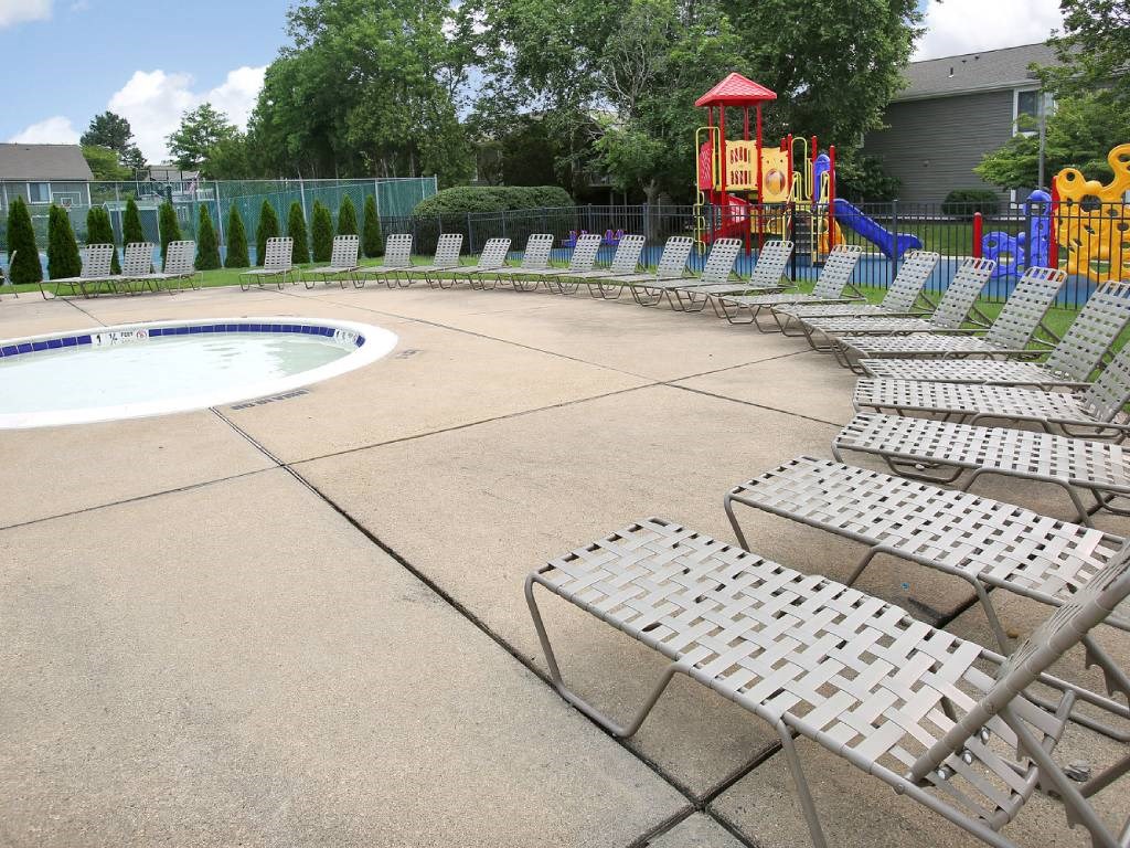 a pool with chaise lounge chairs and a playground in the background