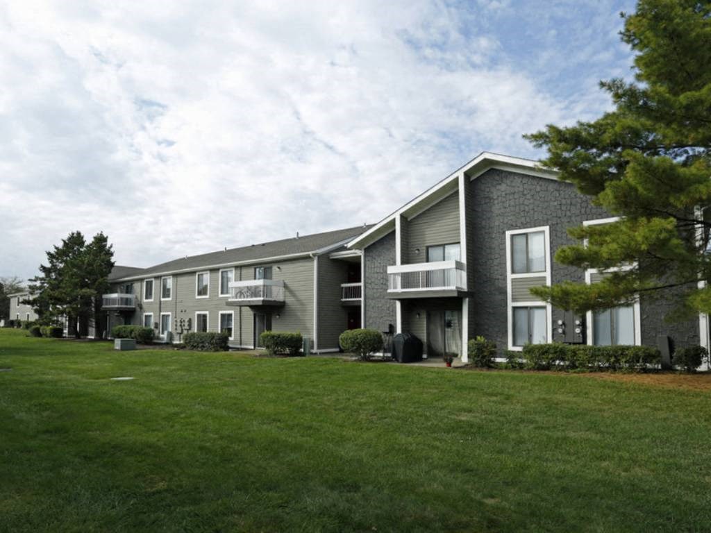 a building with two balconies and a grassy area in front of it