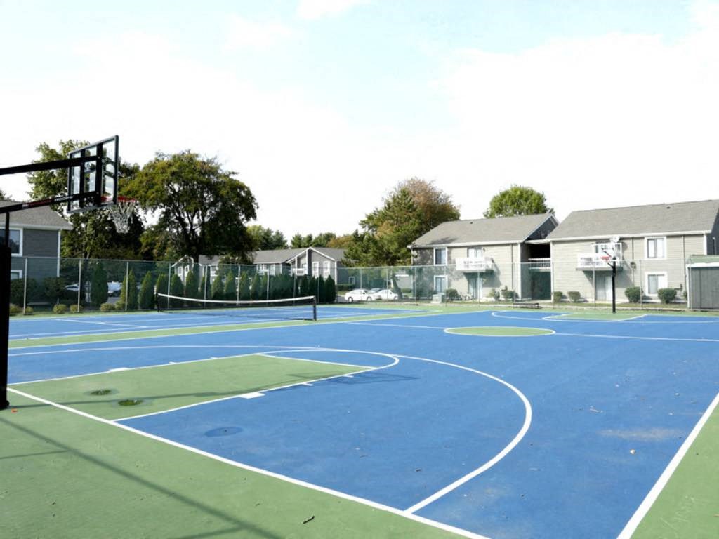 a blue and green basketball court with houses in the background