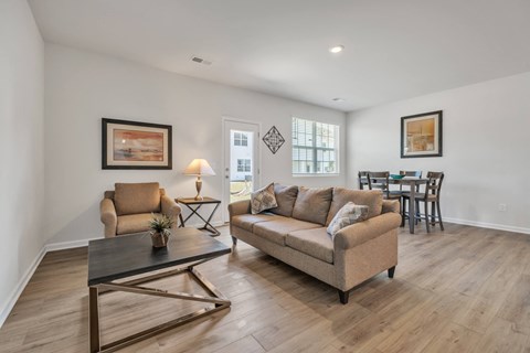 Living room with tan sofa, armchair, and dining table.