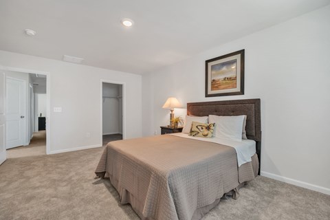 A bedroom with a large bed and a painting on the wall.