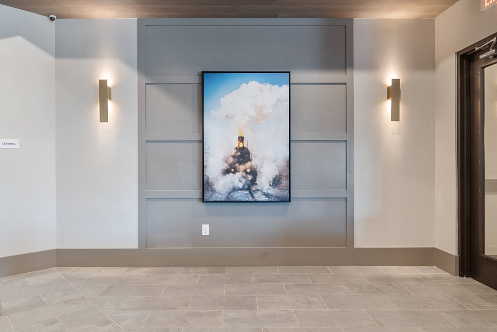 a large painting on the wall in a hallway with two light fixtures and a door