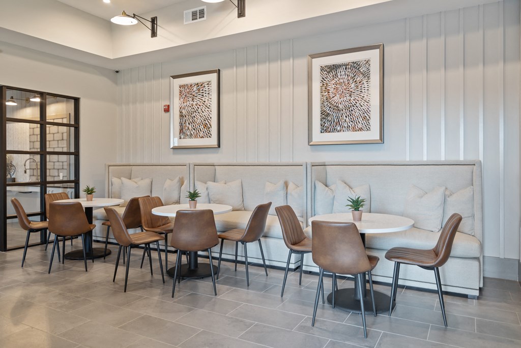 a dining room with tables and chairs and a wall with paintings