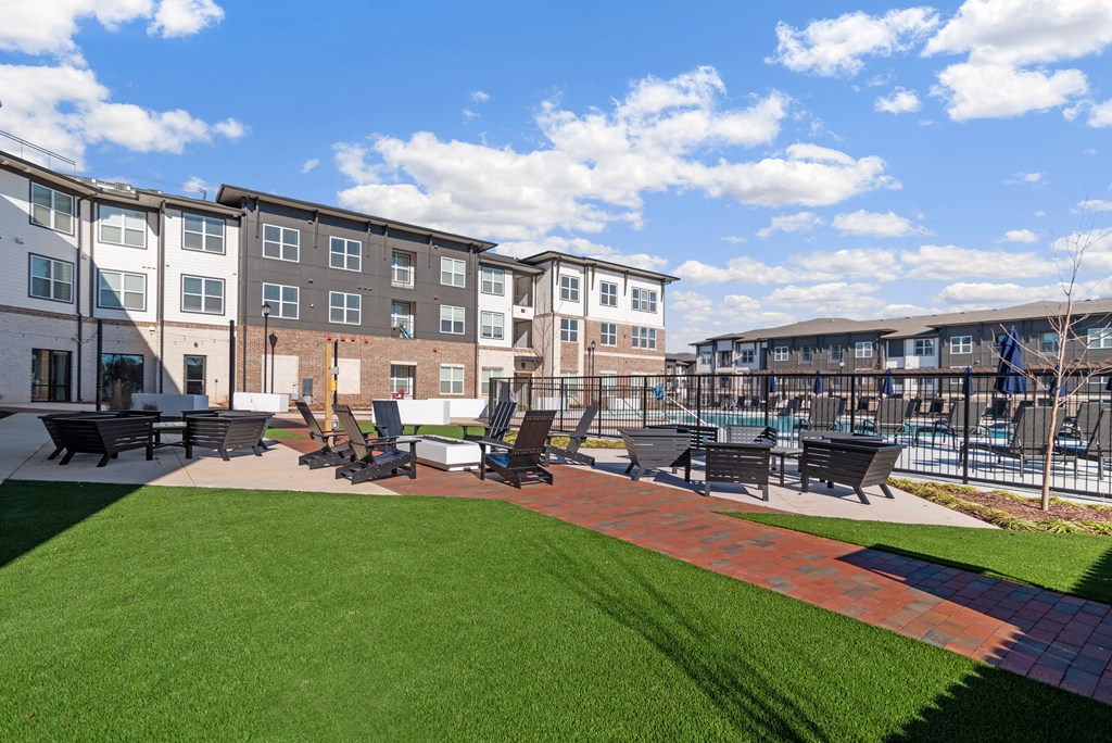 an outdoor lounge area with tables and chairs in front of an apartment building