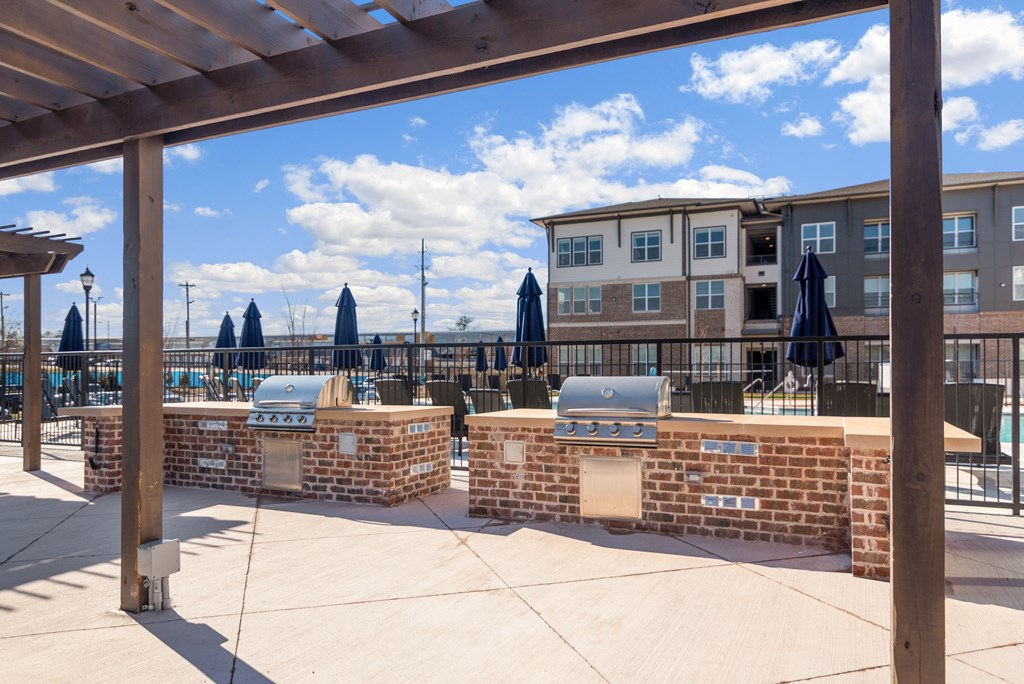 a patio with two bbqs and umbrellas in front of a building