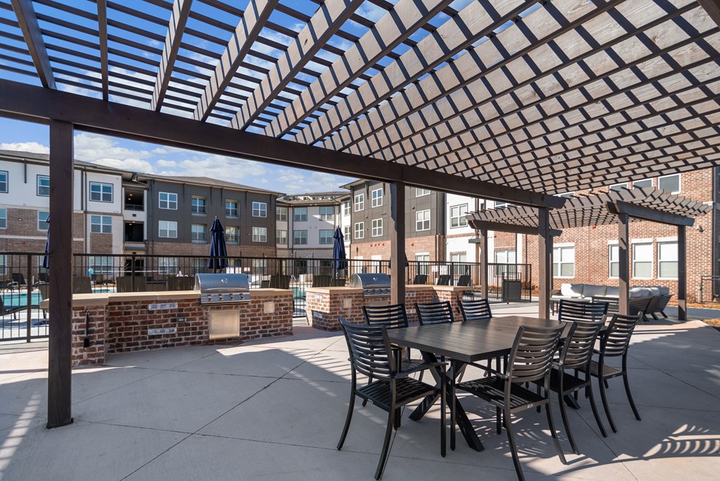 a patio with a table and chairs under a latticed roof