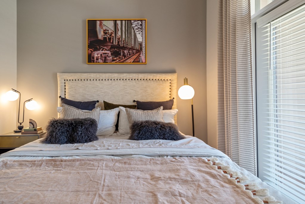 a bedroom with two windows and a bed with pillows