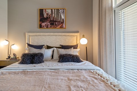 a bedroom with two windows and a bed with pillows