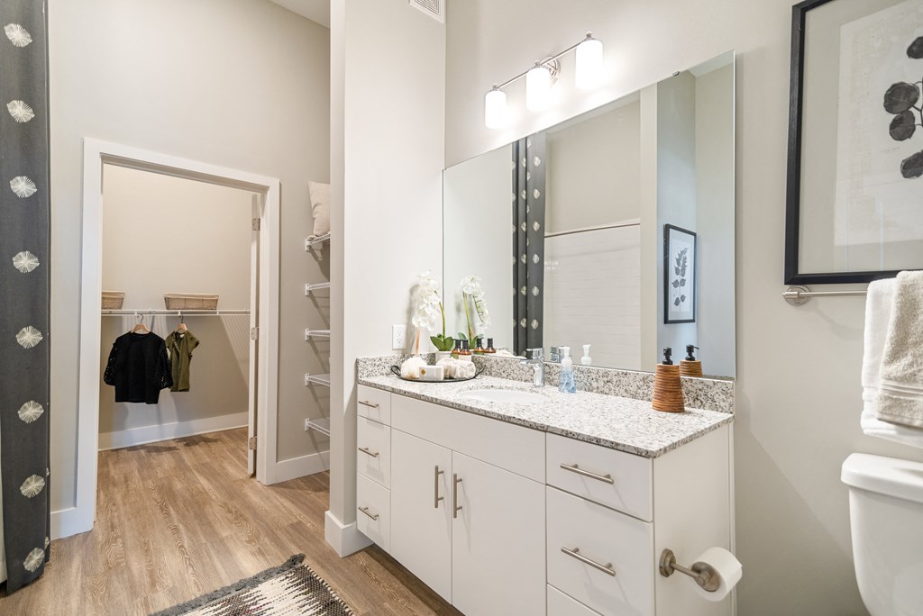 a bathroom with white cabinets and a large mirror and a sink