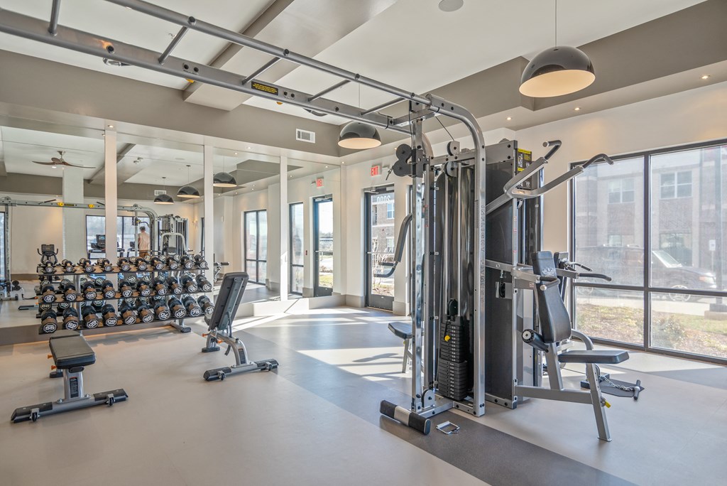 a gym with weights and cardio equipment in a building with large windows