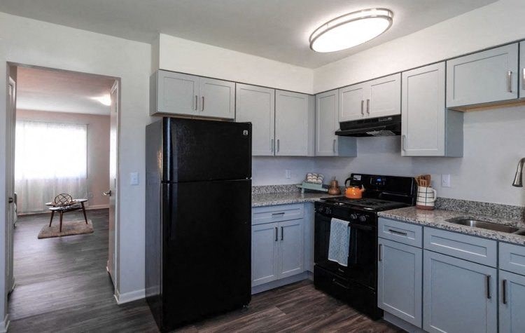 a kitchen with white cabinets and a black refrigerator