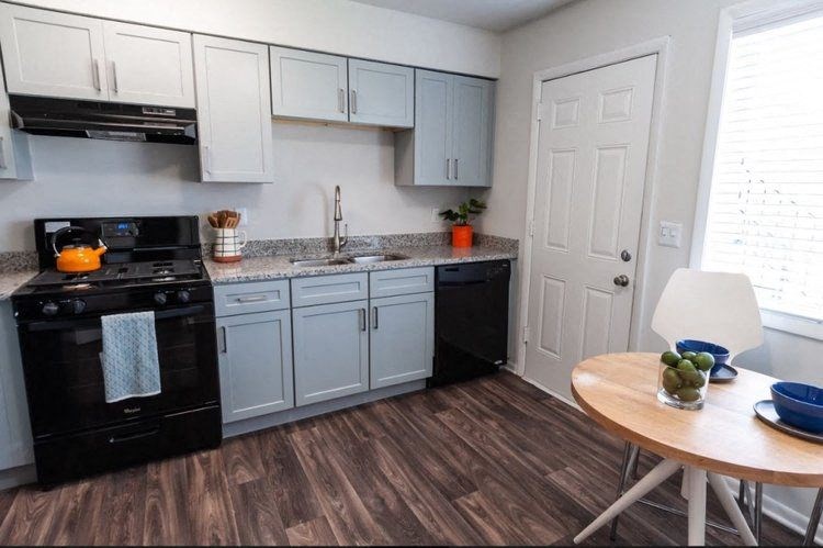 a kitchen with white cabinets and black appliances and a table