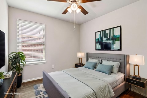 A bedroom with a bed, nightstands, and a ceiling fan.