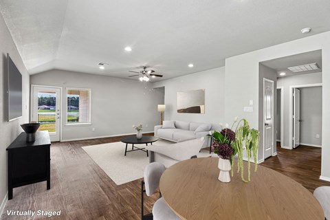 A living room with a couch, a coffee table, and a ceiling fan.