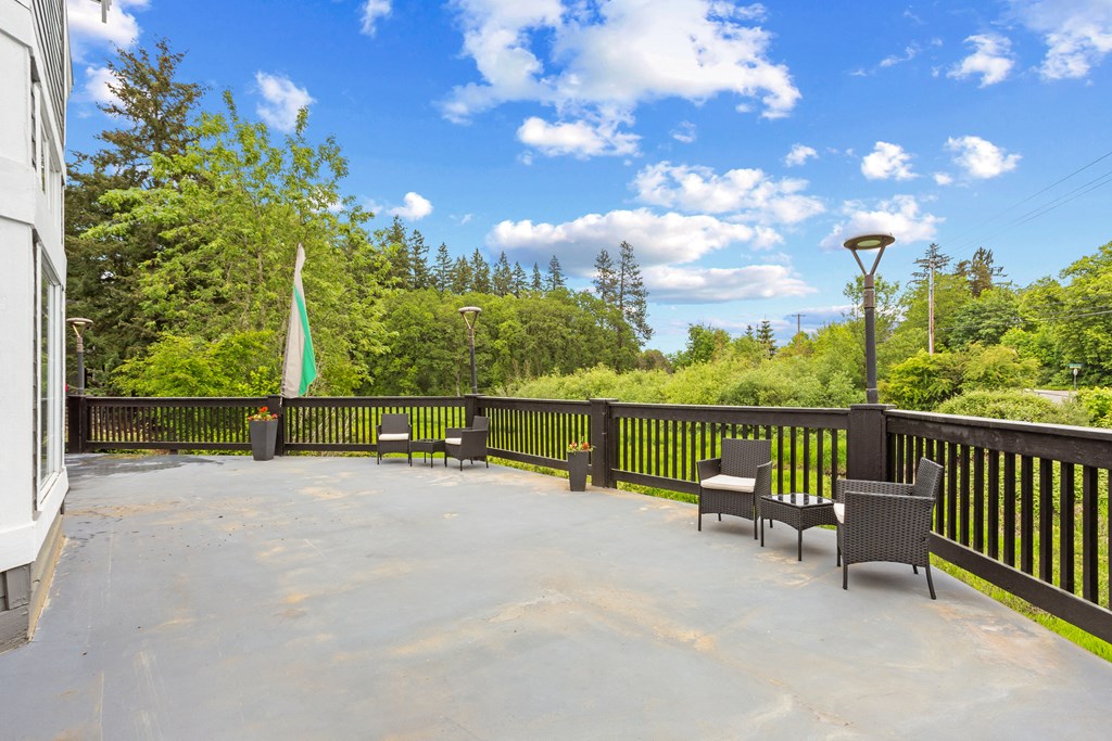 A patio with chairs and a table is surrounded by trees. at Cedar Crest, Beaverton, 97078