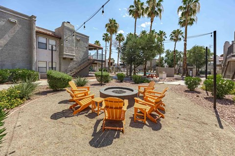 A patio with a fire pit and chairs.