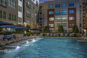 a resort pool with lounge chairs and umbrellas in front of tall buildings