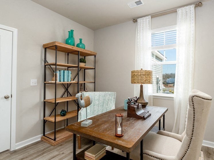 a home office with a large window and a wooden bookshelf