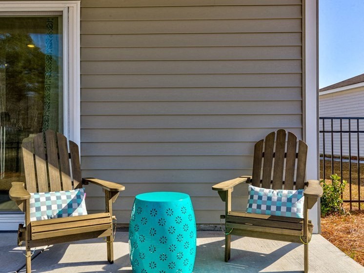 Houses for Rent in Myrtle Beach, SC - The Palmer at Carolina Forest - Spacious Private Patio With a Fenced Yard, Two Wooden Armchairs, and a Blue Side Table