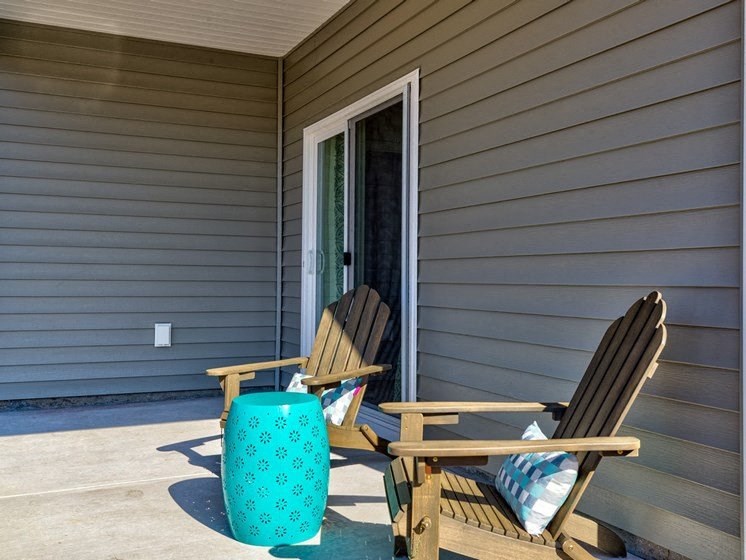 a pair of adirondack chairs sit on a patio in front of a door