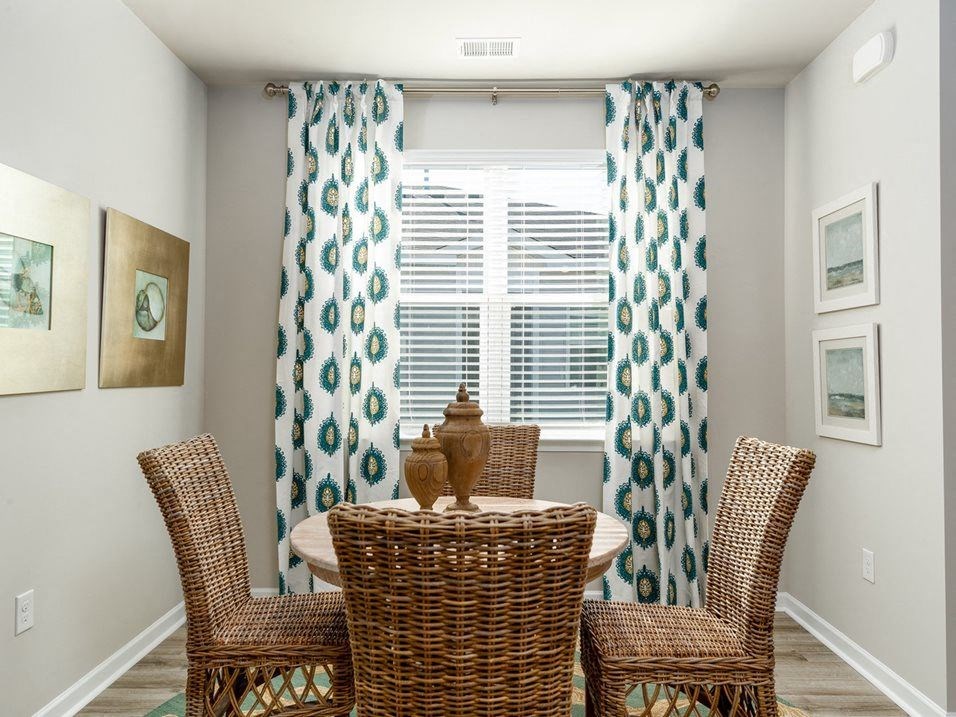 a round table with four chairs in front of a window with curtains