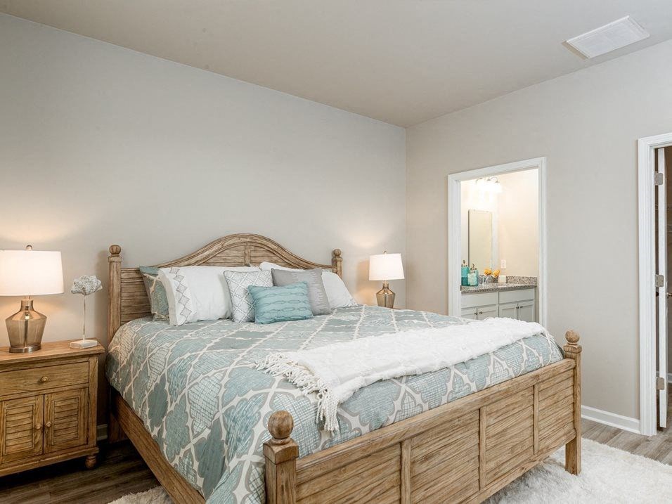 Myrtle Beach Rental Homes - The Palmer at Carolina Forest - Bedroom with Vinyl Plank Flooring, a Rug, a Bed, Two Night Stands, Stylish Decor, and a Bathroom
