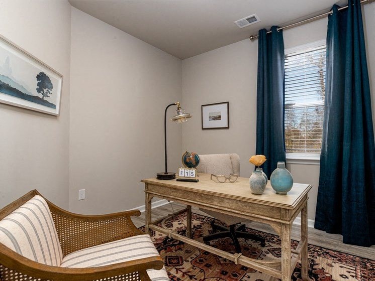 a home office with a desk chair and a window