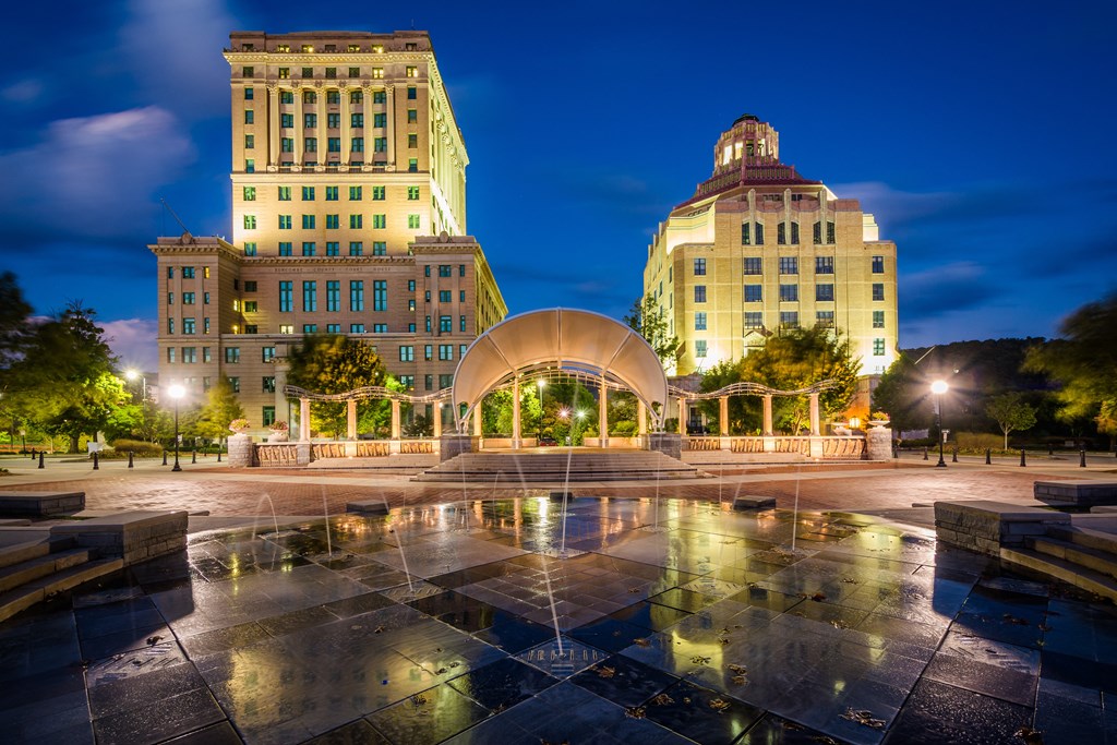 a city at night with buildings and a fountain