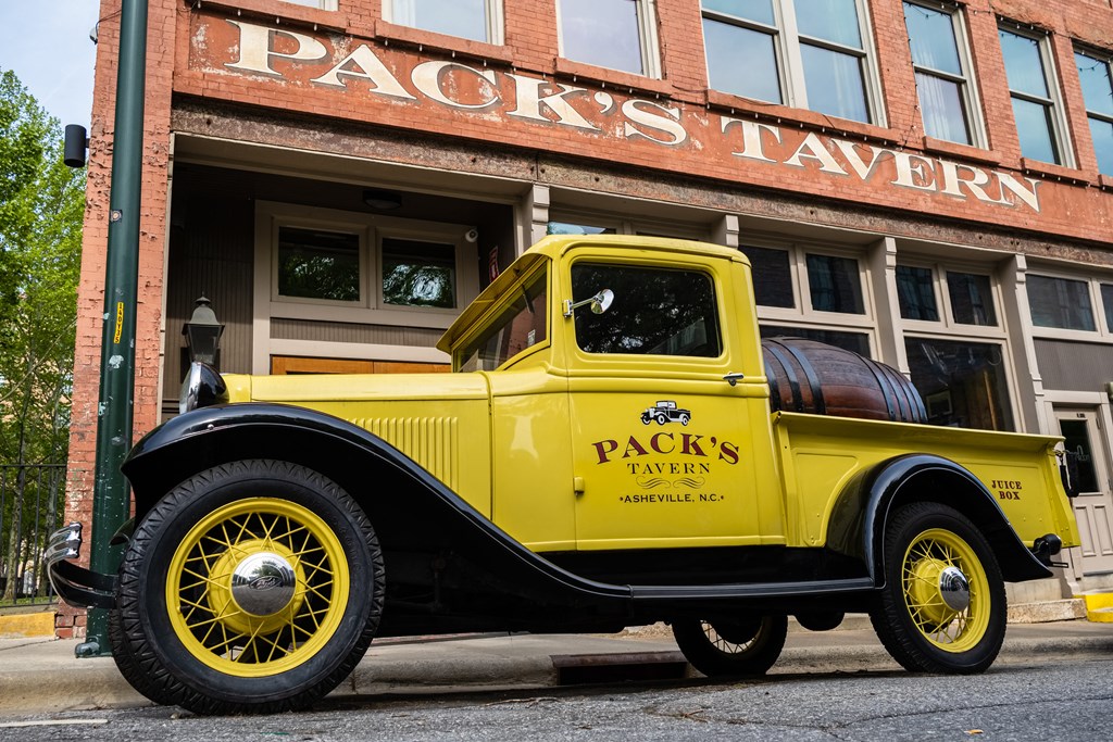 an old yellow truck parked in front of a building