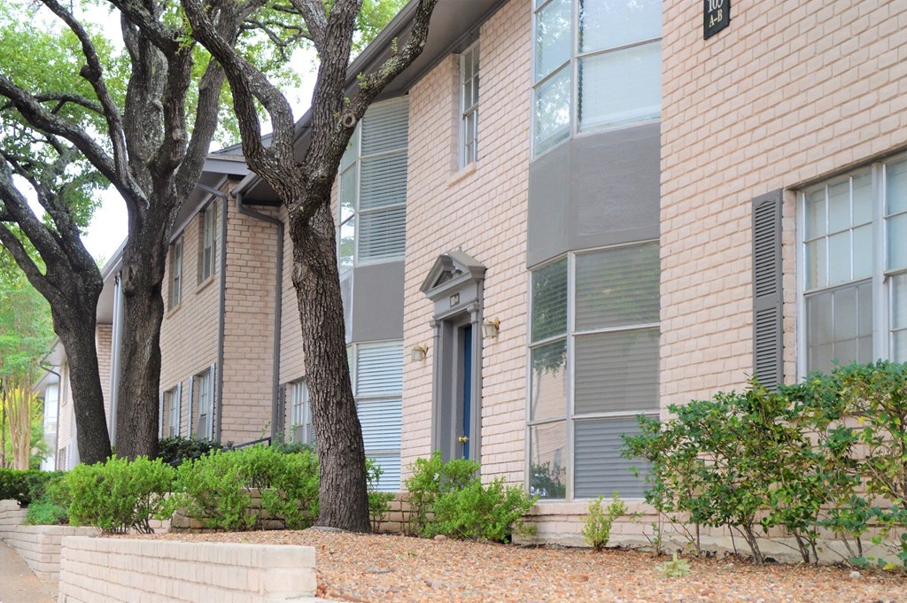 a view of the outside of an apartment building with trees