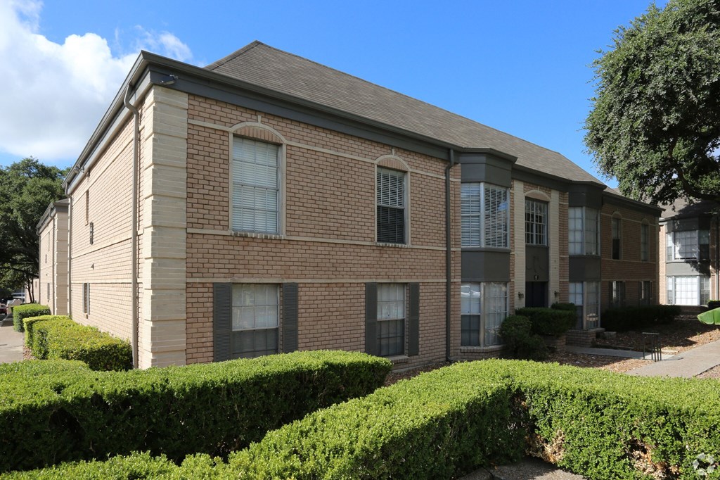 a brick building with hedges in front of it
