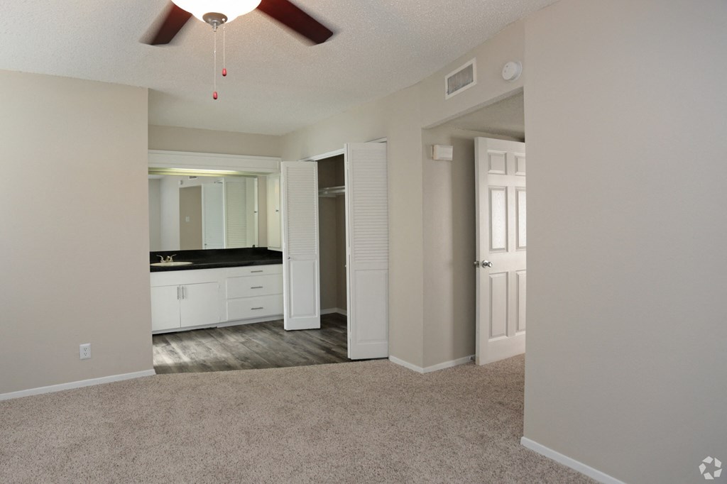 an empty living room with a ceiling fan and a bathroom