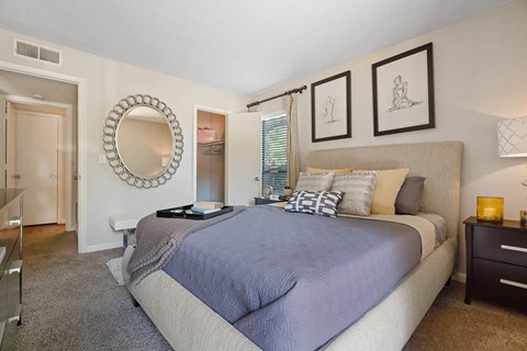 A bedroom with a large bed and a mirror on the wall.