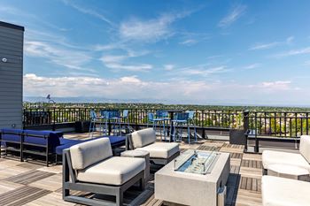 a rooftop deck with couches and tables and a view of the city