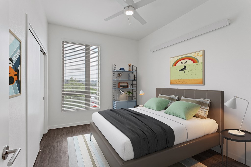 a bedroom with a large window and a ceiling fan