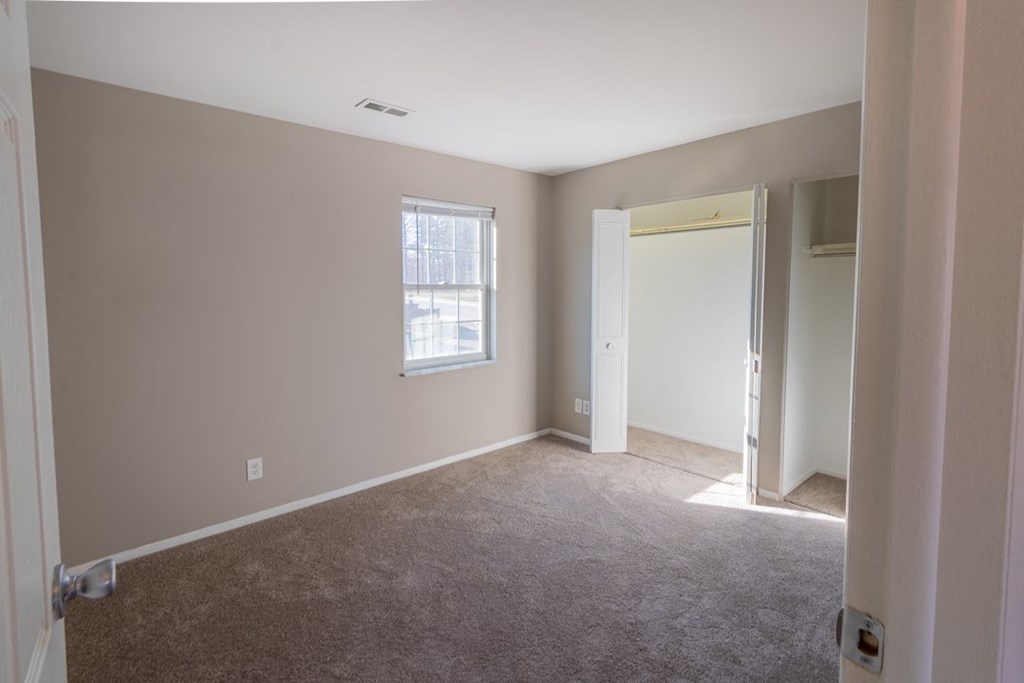 a bedroom with a carpeted floor and a window