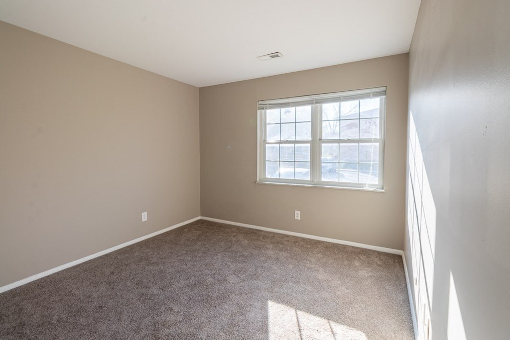 a bedroom with a carpeted floor and a large window