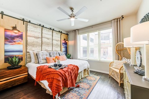 A bedroom with a bed, chair, and a painting on the wall.