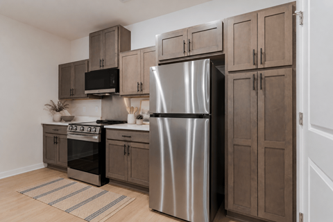 A modern kitchen with a stainless steel refrigerator and wooden cabinets.
