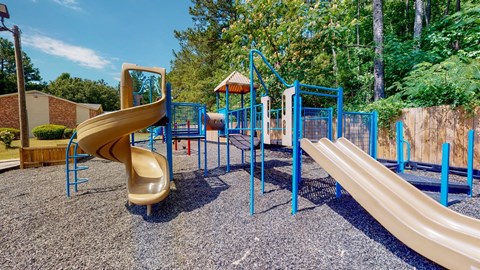 Community playground at Broad on the Green in Augusta, Georgia featuring slides and swings for outdoor recreation.