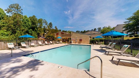 Outdoor swimming pool at Broad on the Green in Augusta, Georgia with lounge seating and umbrellas surrounding the swimming pool.
