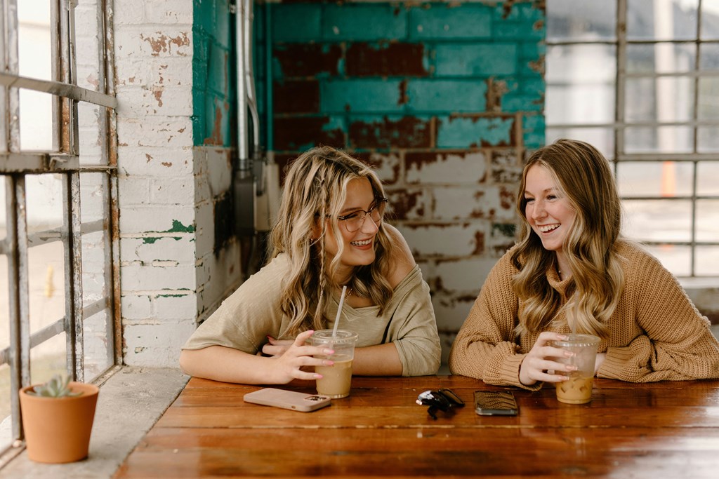 two women sitting at a table drinking coffee