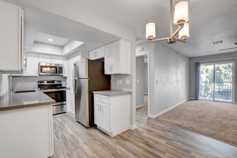 A modern kitchen with white cabinets and a wooden floor.